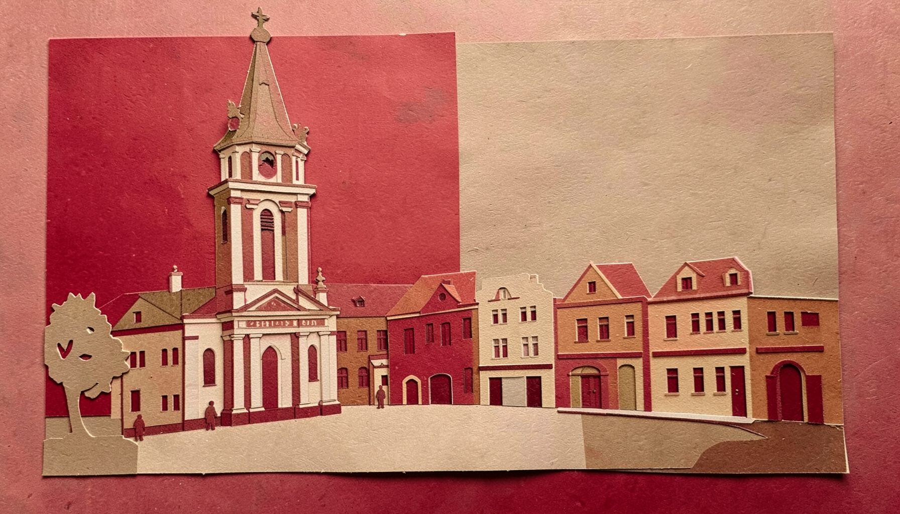 Papírkivágásos kollázs: barokk templomtorony és kisvárosi tér, meleg arany és terrakotta tónusok.